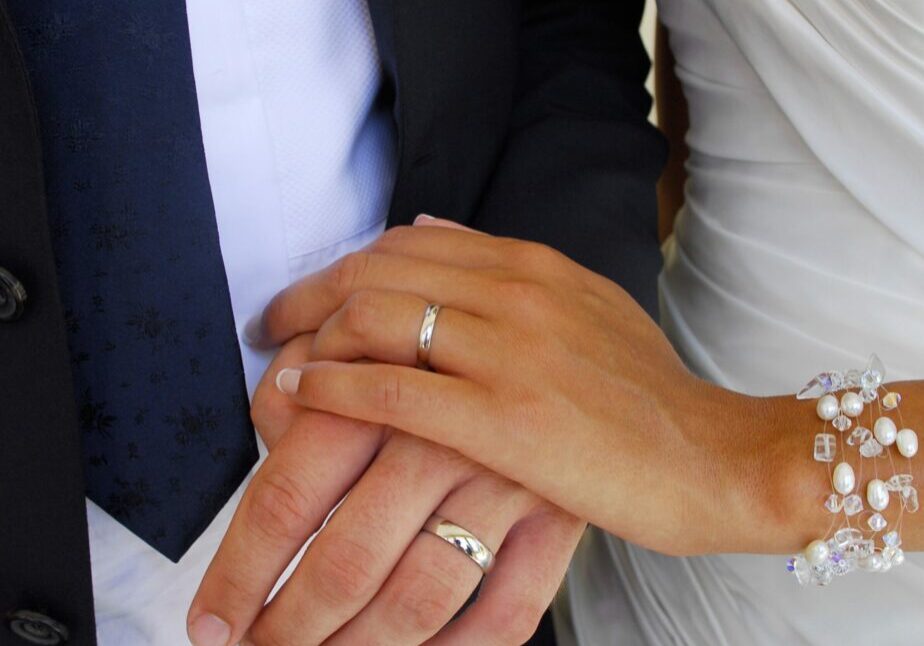 Deux mains entrelacés de mariés avec leurs bagues 